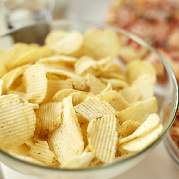 close up of crunchy potato crisps in glass bowl